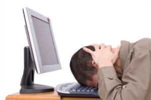 Man resting head on computer keyboard