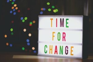 Multicoloured illuminated table-top sign with the words Time for Change against a black blackground containing dots of bright like