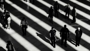 Black and white photo of people in an open space with their shadows visible