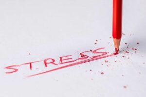The word 'stress' written with a red crayon with crumbling lead