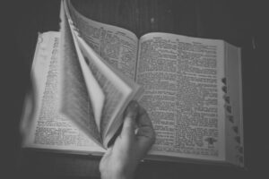Black and white image of a hand leafing through a dictionary