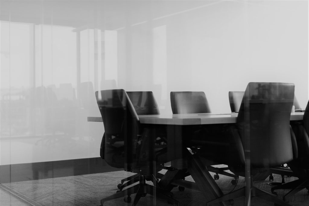 Black chairs around a wooden table in a meeting room.