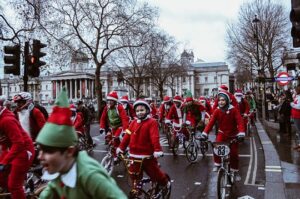 Lots of children and adults on bikes, in Santa and Elves outfits in Trafalgar Square, London.