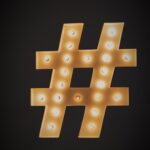 A black background with a hashtag sign in gold, illuminated with little bulbs