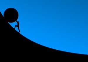 Silhouette of a figure rolling a large stone up a hill