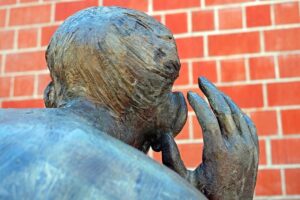 The Listening bronze sculptor looked at from behind. A head and shoulders with a hand up, cupped beside the right hand ear to signal listening - for the Listening Skills tip in our Spring newsletter