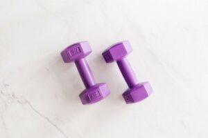 Two purple dumbbells on a white marble surface
