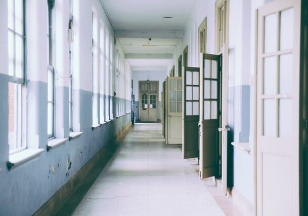 School corridor with windows on one side and classroom doors on other.
